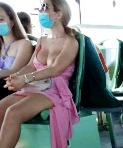 Woman with one boob out on bus wearing face mask.